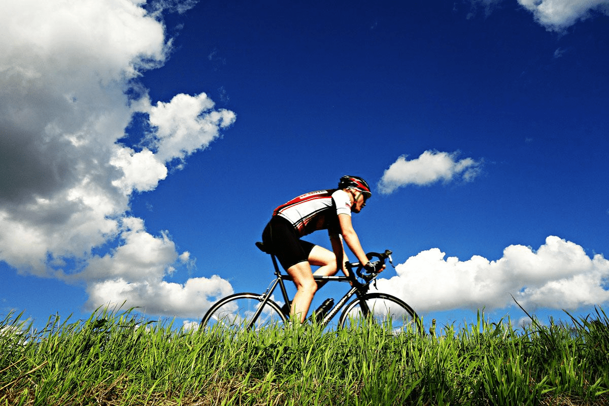 Cyclist riding bike under blue sky.